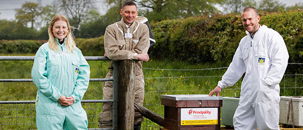 Image of a Principality colleague with the founders of Gwenyn Gruffydd beehives at the beehive.